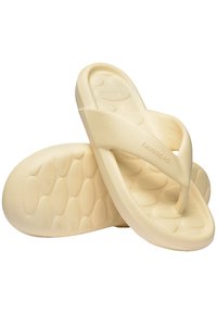 Béžové šľapky s textúrovanou podr�ážkou a hladkými, širokými popruhmi. Názov značky "Havaianas" je embosovaný na jednom popruhu.
