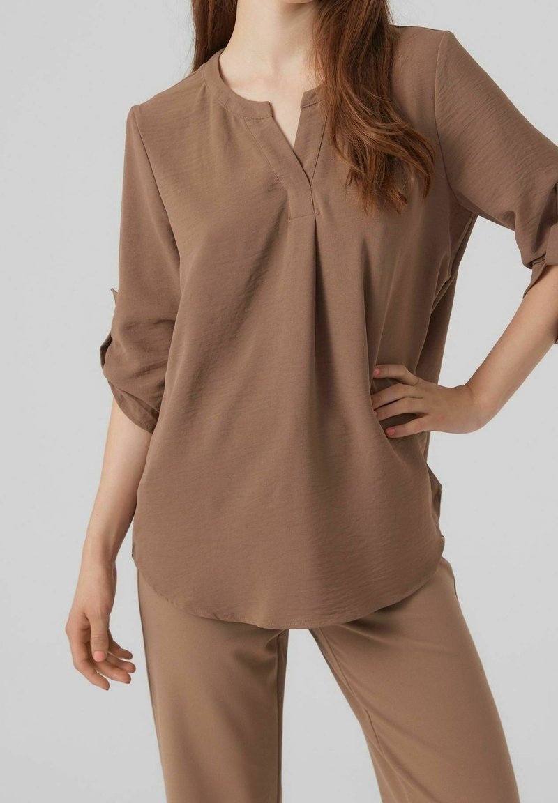 Blusa marrone leggera con apertura a metà bottone e maniche a ¾, abbinata a pantaloni coordinati, caratterizzati da una texture liscia.