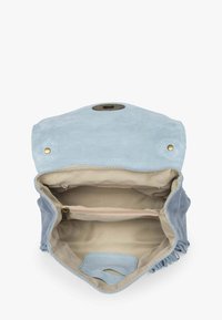 Světle modrá semišová crossbody taška otevřená, aby ukázala béžovou látkovou podšívku, kapsu na zip a magnetické zapínání na klopě s kovovými detaily.