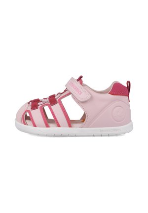 Sandalia infantil rosa con parte superior sintética, diseño abierto, correas elásticas y suela de goma blanca. Presenta un logo decorativo en el lateral.