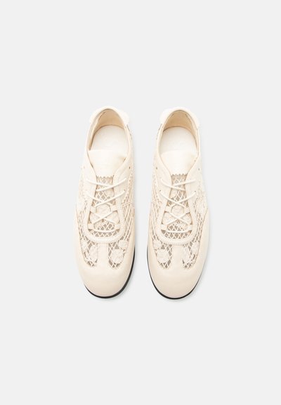 Ζευγάρι μπεζ παπουτσιών με κορδόνια, με λεπτομέρειες από δίχτυ και κεντήματα με λουλούδια, εμφανιζόμενα από πάνω σε απλό ανοιχτό φόντο.