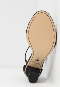 Vue de la semelle d'une sandale noire à talon carré, semelle beige, avec la taille 37 indiquée près du talon.