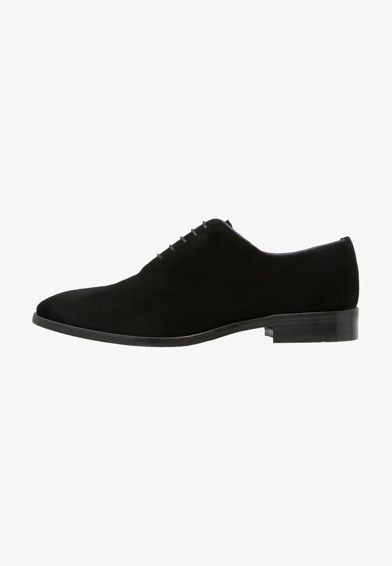 Chaussure Oxford homme en daim noir avec laçage fermé, talon bas empilé et bout arrondi, vue de profil.