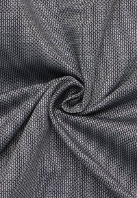 Textil mit einer strukturierten Oberfläche, dunkelblaubem Hintergrund und abstrakten, hellen Blattmustern. Weich und mit glatter Oberfläche, ideal für Kleidung oder Polsterungen.