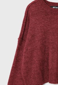 Pull en maille bordeaux doux avec une texture, col rond côtelé, poignets et ourlet, présenté sur un fond clair.
