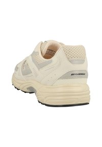 Hellbeige Sportschuh aus einem Mesh- und Synthetikmaterial, mit einer gepolsterten Sohle, einer strukturierten Oberseite und subtilen grauen Akzenten.