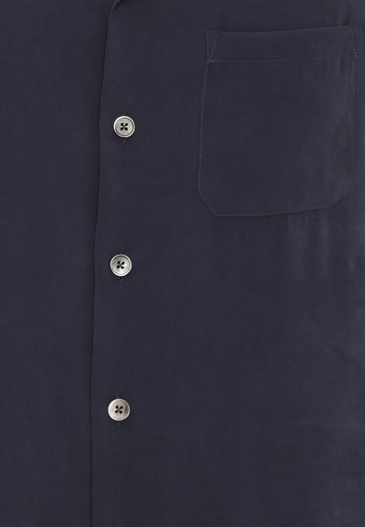 Camisa de botones azul marino con un bolsillo en el pecho, cierres de botones plateados y una textura suave y mate.