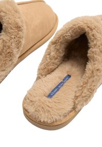 Zapatillas de casa beige sin cordones con un interior mullido y esponjoso y un exterior suave, con una suela texturizada y un borde cosido.