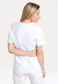 White cotton t-shirt with short sleeves, round neckline, and a smooth texture. Minimalist design with no visible logos or patterns.