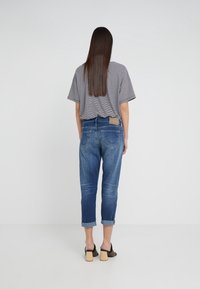 Siniset denim-farkut kapealla leikkauksella, käärityt lahkeet ja takataskut. Yhdistetty harmaaseen, raidalliseen lyhythihaiseen toppiin ja korkokenkiin.