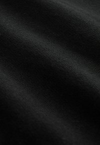 Tela negra con una textura suave, que presenta líneas o pliegues horizontales sutiles. El material parece suave y tiene un tejido denso.