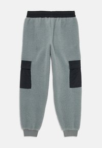 Šedé fleecové jogger kalhoty s černým elastickým pasem, černými cargo kapsami na stehnech a žebrovanými manžetami na kotnících.