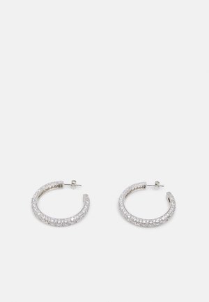 Boucles d'oreilles créoles ouvertes en argent incrustées de petites pierres précieuses claires, sécurisées par des fermoirs à tige, présentées sur un fond clair uni.