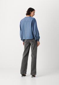 Lys blå denimjakke med lange pufferm, litt kort design. Kombinert med høyt liv, falmede svarte vide bukser.