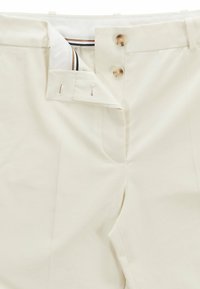 Spodnie w kremowym kolorze z płaskim przodem, dwoma przednimi kieszeniami oraz guzikami w złotym odcieniu w pasie. Gładka tkanina o subtelnej fakturze.