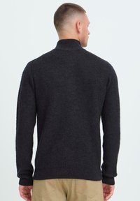 Donkergrijze, geribbelde gebreide trui met een hoge kraag en lange mouwen, met een ontspannen pasvorm en een gestructureerde stof.