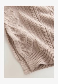 Suéter de punto color beige claro con patrones de cable, puntos texturizados y un dobladillo acanalado. Tejido suave y acogedor con detalles intrincados.