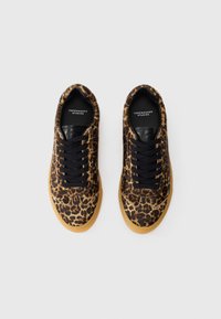 Baskets à imprimé léopard avec une languette en cuir noir, des lacets noirs et une semelle en caoutchouc. Tige texturée pour plus de détails.