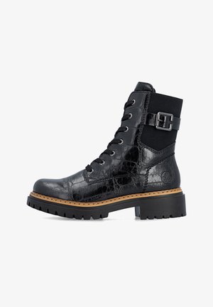 Botte noire en cuir à lacets avec semelle épaisse crantée, détail de boucle sur le côté et trépointe marron cousue, vue de côté sur fond blanc.