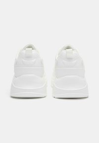 Sneaker sportive bianche con una texture liscia, tallone imbottito e linguetta di aiuto. Il design presenta sottili accenti con il logo e una suola spessa.