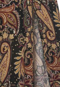 Crni materijal s kompleksnim paisley uzorcima u zlatnoj, burgundskoj i zelenoj boji s cvjetnim naglascima i detaljno izvedenim šavovima.