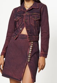 Denim jacket and skirt set in dark reddish-purple. Jacket features button pockets and cut-out detail. Skirt has side buttons and a slit.