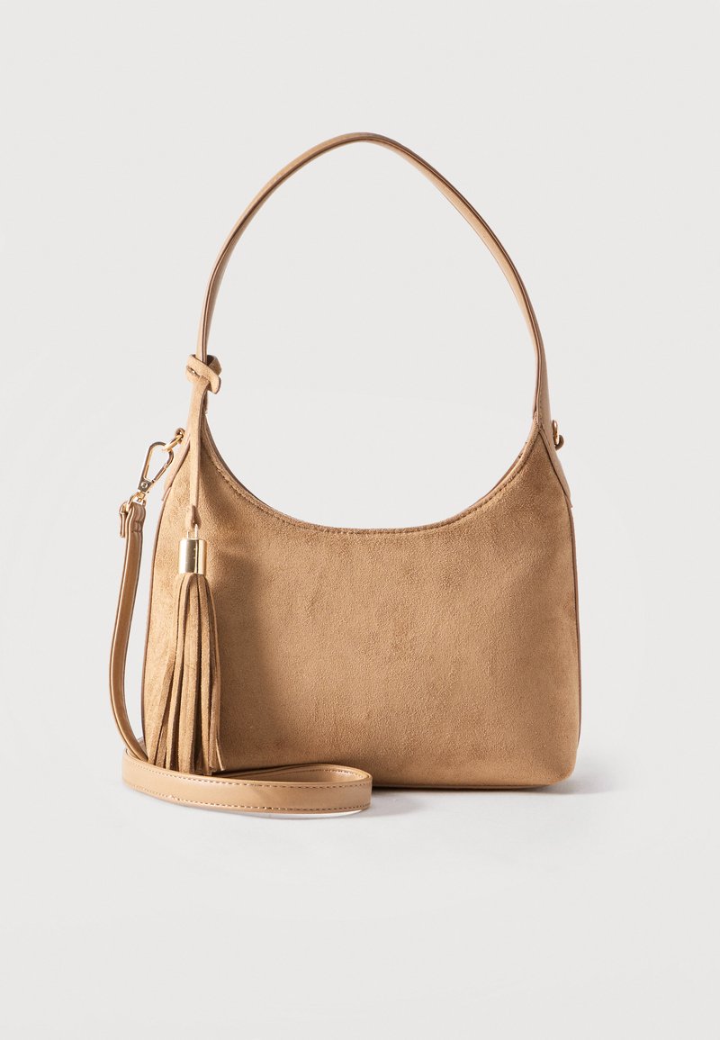 Gaiši brūna zamšāda rokassoma ar vienu plecu siksnu, noņemamu pāri ķermenim nēsājamu siksnu un saskaņotu zamšāda pušķa detaļu.