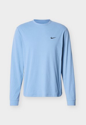 Helehall sinine puuvillane pika varrukaga T-särk, millel on ümargune kaelus ja väike must Nike logo vasakul rinnal.