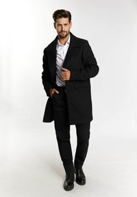 Palton negru din lână cu guler cu decupaj, buzunare frontale și tăiere ajustată, asortat cu pantaloni negri și pantofi cu șireturi negre.