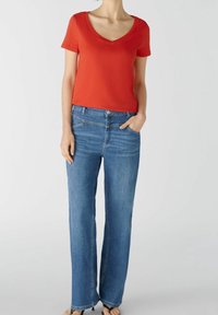 Rode korte mouwen v-hals t-shirt gecombineerd met blauwe wijde jeans met knoop- en ritssluiting, zijzakken en subtiele vervaging.