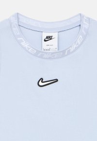 Ανοιχτό μπλε μπλουζάκι Nike Dri-Fit με ραβδωτή υφή, που διαθέτει μαύρο λογότυπο Nike και λευκές λεπτομέρειες με σήμανση στη λαιμόκοψη.