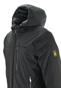 Giacca nera isolata con cappuccio, caratterizzata da una texture liscia, tasche con zip e una toppa logo sulla spalla.