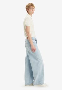 Lys blå vide jeans med høy midje, laget av denim; har et klassisk fem-lomme design og subtile sømdetaljer.