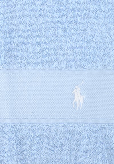 Φωτεινό γαλάζιο υφασμάτινο πετσέτα με υφαντή ταινία που διαθέτει λευκό κεντημένο λογότυπο παίκτη πόλο στο κέντρο.