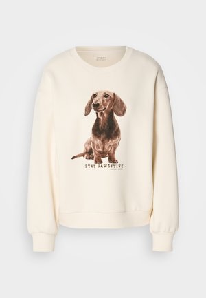 Sweatshirt couleur crème avec un imprimé détaillé d'un teckel et le texte "RESTEZ POSITIF," avec des poignets et un ourlet côtelés.