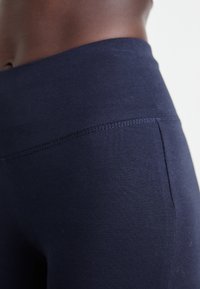 Marineblaue Leggings aus einem glatten, strukturierten Stoff mit einem breiten, hohen Bund. Mit flachen Nähten für zusätzlichen Komfort.