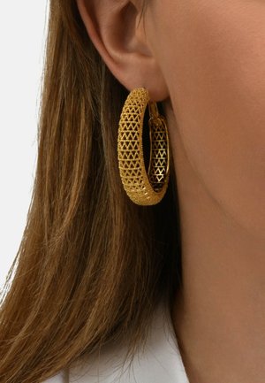 Boucles d'oreilles en or en forme de créole avec un design texturé et tissé présentant un motif géométrique. Les boucles d'oreilles sont grandes et rondes, avec une finition lisse.