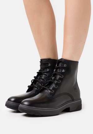 Zwarte leren enkellaarsjes met een gladde afwerking, een ronde neus, zeven oogjes voor veterstrik aan de voorkant, en een gestructureerde rubberen zool met logodetail.