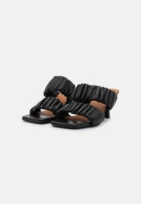 Sandálias pretas com salto bloco largo, com tiras de tecido franzidas e um design de bico quadrado. Textura suave e estilo minimalista.