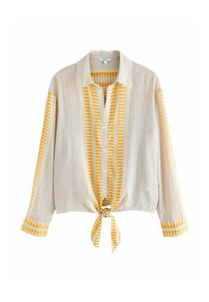 Chemise beige à manches longues avec fines rayures et motifs triangulaires jaunes verticaux, boutonnée sur le devant et nouée à la taille.