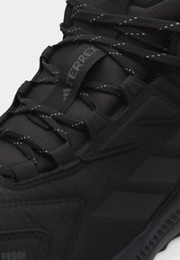 Κοντινή λήψη μαύρου παπουτσιού πεζοπορίας Terrex με υφασμάτινη υφή, κορδόνια με σχέδιο και ανθεκτική σόλα σχεδιασμένη για υπαίθρια χρήση.