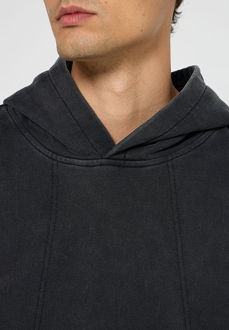 Dunkelgrauer Hoodie mit geripptem Muster, übergroßer Kapuze und genähten Details entlang der Nähte.