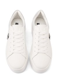 Des baskets blanches avec une tige en cuir lisse, un bout arrondi et une semelle en caoutchouc plate. Les caractéristiques comprennent des lacets et un panneau arrière texturé.