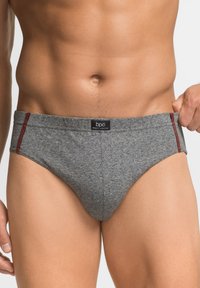 Slip in cotone grigio con accenti laterali rossi, dotato di una cintura flessibile e di una texture liscia. L'etichetta frontale mostra il nome del brand "bpc".