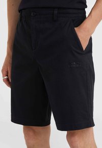 Schwarze Baumwollshorts mit flachem Vorderteil, Gürtelschlaufen und seitlichen Taschen; mit gesticktem Logo auf dem Oberschenkel und geradem Saum.