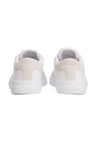 Ein Paar weiße Low-Top-Sneaker mit beigefarbenen Wildleder-Fersenpatches, von hinten auf einem weißen Hintergrund betrachtet.