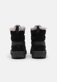Czarne zimowe buty z puszystym szarym futerkiem, wykonane z miękkiego zamszu i materiału syntetycznego, z teksturowaną gumową podeszwą i pętlą do zakupu.