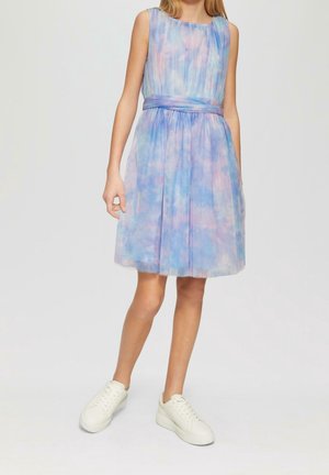 Robe sans manches en bleu pastel et violet avec un design plissé, une ceinture assortie à la taille et une jupe évasée. Portée avec des baskets blanches.