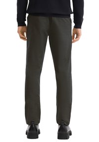 Pantaloni slim fit neri realizzati in tessuto liscio, con vita media e gambe dritte. Indossati con stivali neri alla caviglia.