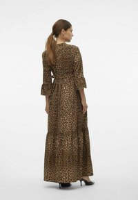 Maxiklänning med leopardmönster, utställda ärmar, knytmidja och ett lager på lager-tyg. Har en mjuk yta på en brun bas med mörka fläckar.